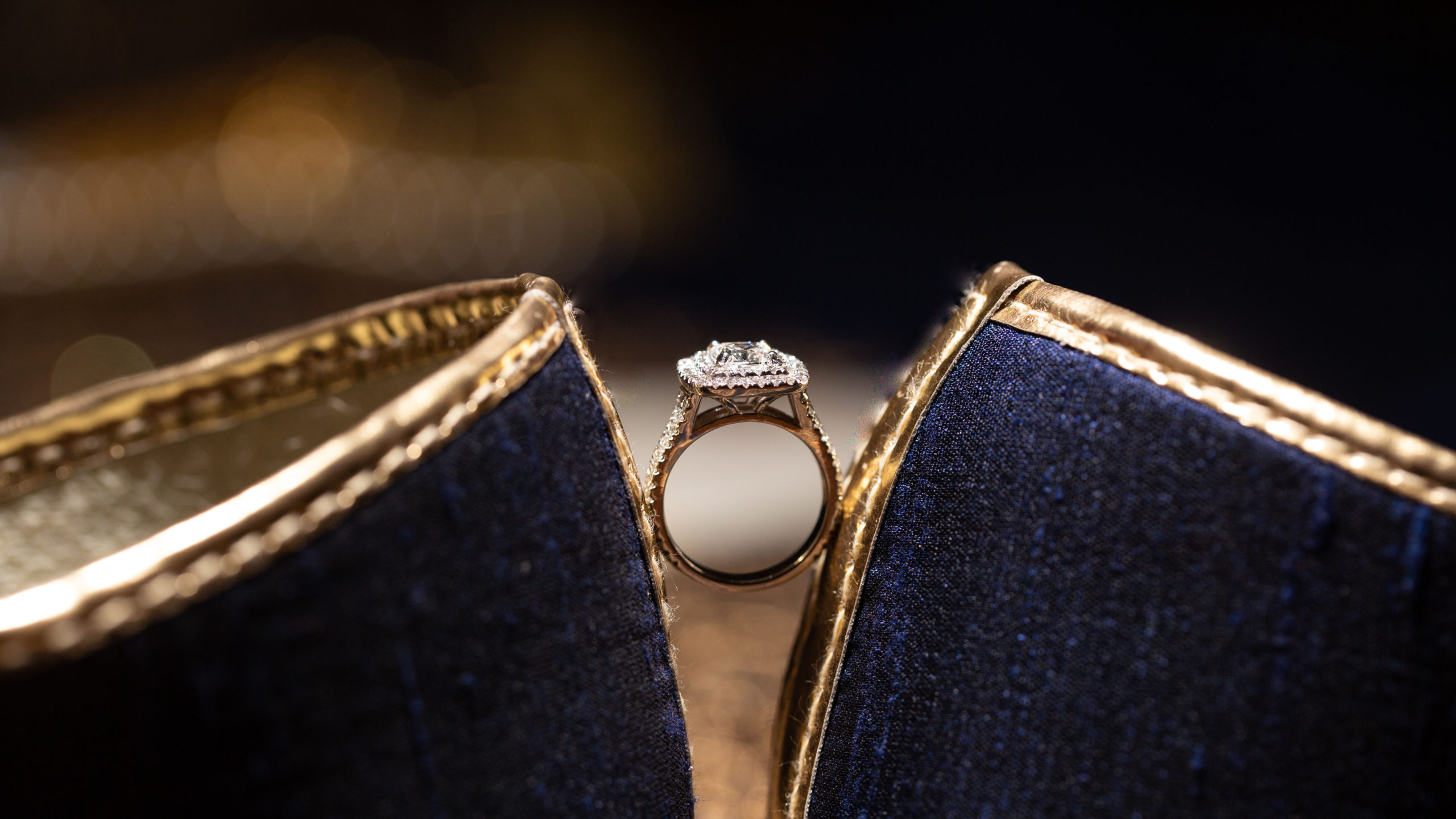 Engagement ring posed between a pair of stunning gold rimed shoes